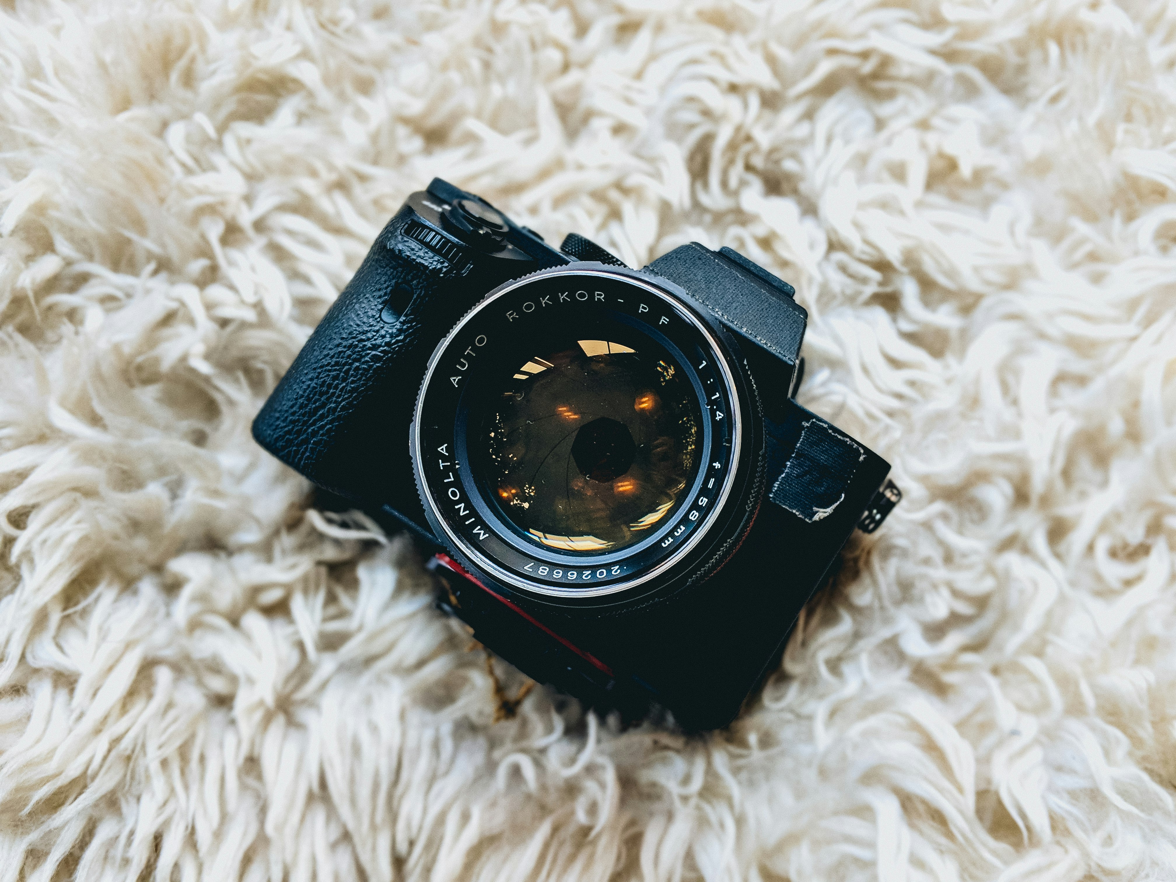 black milc camera on white fur cloth